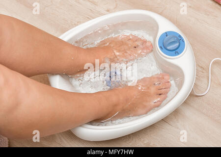 Les pieds dans un tamis vibrant massage des pieds. Bain de pieds massage électrique. Pédicure et soins des pieds Banque D'Images