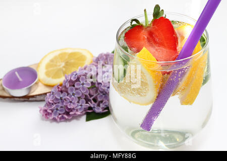 L'eau aromatisée au citron détox, concombre et fraise sur fond blanc avec décoration en bois et de lilas. Concept d'aliments sains. Banque D'Images