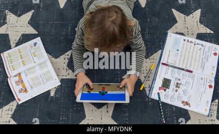 Garçon, école primaire, 8 ans, apprend à l'école à la maison, devoirs, n'utilise un ordinateur tablette pour l'apprentissage, jeu vidéo dans une pause, Banque D'Images