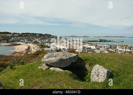 Fin du Néolithique chambre funéraire et Hughtown avec capstone et Porthcressa, St Mary, Îles Scilly, au Royaume-Uni, à l'arrière-plan ; journée ensoleillée avec un ciel bleu Banque D'Images