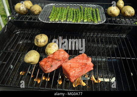 La pastèque, les pommes de terre et les asperges cuisent sur le barbecue de la cour extérieure le dimanche après-midi d'été. Banque D'Images