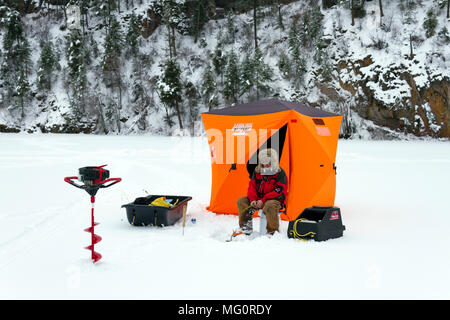 Yellow Lake, Colombie-Britannique, Canada - le 7 janvier 2018 : Man Ice fishing pour la truite sur une froide journée d'hiver sur le lac jaune congelé près de Penticton, Brit Banque D'Images