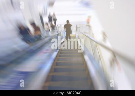 Motion Image floue de l'homme Hoding Moblie Phone et Comité permanent sur l'Escalator. Banque D'Images