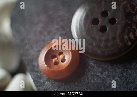 Petit bouton vêtements en bois à côté d'un grand bouton vêtements nontissé aiguilleté sur l'arrière-plan. Vue Macro, profondeur de champ. Banque D'Images
