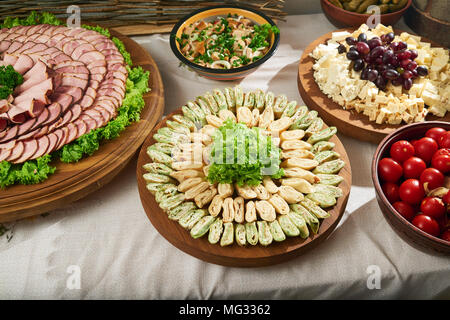 Table de restaurant plein de tapas différents apéritifs : bobines avec légumes, bol de tomates marinées, assortiment de viande, fromage et raisin frais avec assortiment de champignons marinés. Banque D'Images