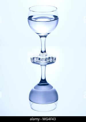 Seul verre a pied d'eau isolé sur un fond blanc avec miroir de réflexion. Banque D'Images