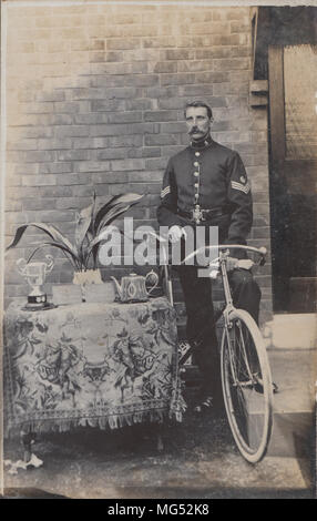 Véritable Carte postale photographique d'un sergent de police était assis sur un vélo à côté d'une table de Trophées Banque D'Images