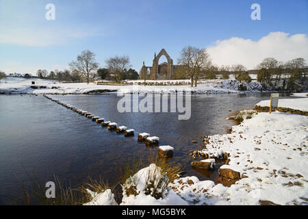 River Wharfe circulant par des tremplins par Bolton Prieuré entouré de neige de l'hiver par Bolton Abbey Yorkshire Dales UK Banque D'Images