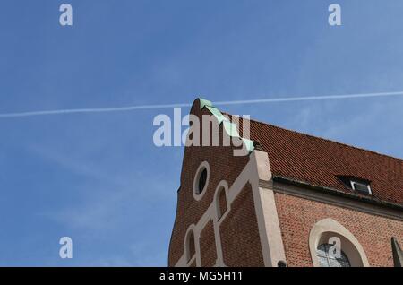 Bâtiment historique faite de briques rouges et d'une traînée de condensation d'un avion dans le ciel bleu tourné à Munich en Allemagne Banque D'Images