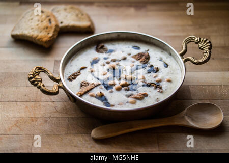 Yuvalama turc avec soupe de yaourt et de pois chiches dans un bol de cuivre sur une surface en bois. Banque D'Images