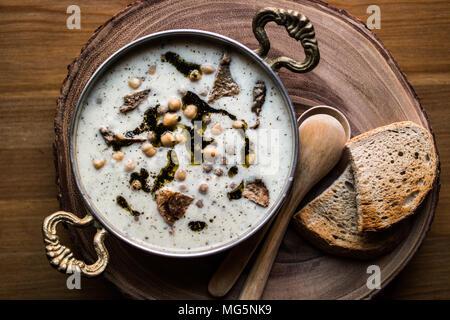 Yuvalama turc avec soupe de yaourt et de pois chiches dans un bol de cuivre sur une surface en bois. Banque D'Images