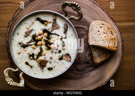 Yuvalama turc avec soupe de yaourt et de pois chiches dans un bol de cuivre sur une surface en bois. Banque D'Images