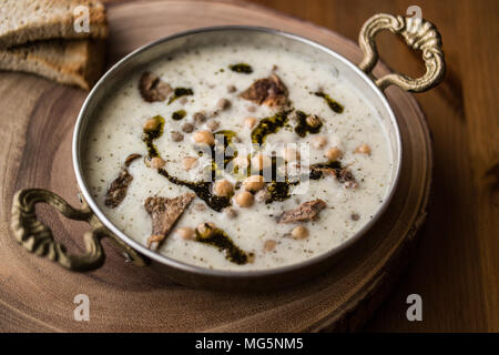 Yuvalama turc avec soupe de yaourt et de pois chiches dans un bol de cuivre sur une surface en bois. Banque D'Images