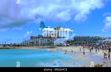 MAHO, SAINT MARTIN - 27 février 2018 : un avion vole InselAir bas au-dessus de la plage Maho comme il se prépare à atterrir à l'Aéroport Princess Juliana SXM derrière. Banque D'Images