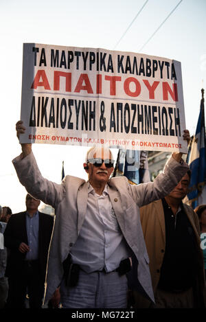 Athènes, Grèce. Apr 27, 2018. Un manifestant vu holding a placard pendant la manifestation.Premier rassemblement au monument du Soldat inconnu, la progression s'est faite jusqu'à l'Ambassade pour protester pour la compensation de la Deuxième Guerre mondiale, de l'Allemagne comme plusieurs le massacre perpétué par les soldats allemands en 1943 ont été commis. Credit : Vangelis/Evangeliou SOPA Images/ZUMA/Alamy Fil Live News Banque D'Images