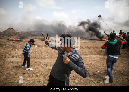 Khan Younis, dans la bande de Gaza. Apr 27, 2018. Les manifestants lancer des pierres vers les forces de sécurité israéliennes au cours d'affrontements le long de la frontière, Israel-Gaza à Khan Younis, dans la bande de Gaza, 27 avril 2018. Les Palestiniens protestent pour le 5ème vendredi d'une ligne dans le cadre d'une période de six semaines de protestation, le long de la frontière Gaza-Israel, à la demande de retourner dans leurs foyers qu'ils ont été expulsés de lors de la guerre de 1948 qui a marqué la création d'Israël. Credit : Wissam Nassar/dpa/Alamy Live News Banque D'Images