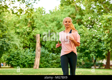 Une belle jeune femme blonde qui traverse un champ dans un parc Banque D'Images