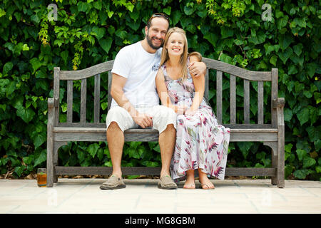 Smiling couple sur banc en bois Banque D'Images