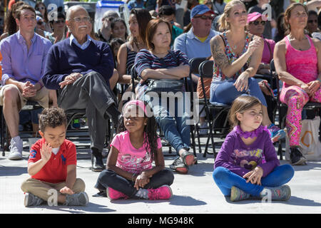 Groupe diversifié d'enfants assis sur le trottoir en spectacle. Banque D'Images
