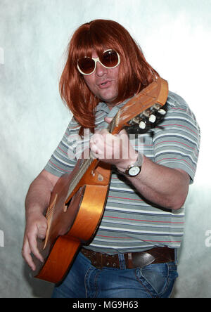 Guitariste avec longs cheveux rouges joue de la guitare et chante quelque chose. Banque D'Images