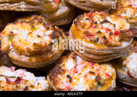 Portions délicieuses tartes mini ronde faite de pâte feuilletée croustillante farcie aux oeufs oignon vert et la chair de crabe et faire fondre le fromage cuit au four et de piles Banque D'Images