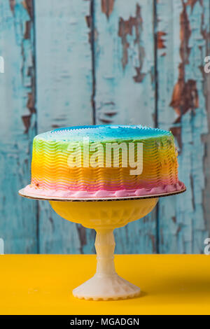 Rainbow cake givré jaune avec table et fond bleu Banque D'Images