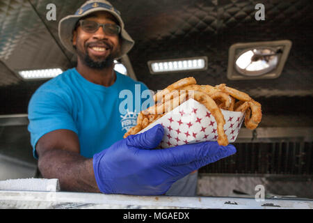 Portrait d'un propriétaire de petite entreprise dans son camion alimentaire avec un panier plein d'oignon frit Banque D'Images