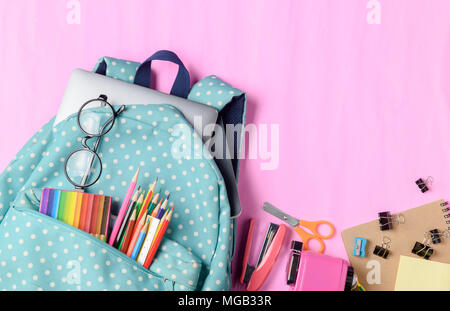 Sac à dos pour l'école avec des crayons de couleur et de matériel scolaire sur fond de papier rose. Concept Retour à l'école. Banque D'Images