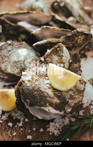 Oyster shell ouvert avec le citron et le sel sur une planche en bois Banque D'Images