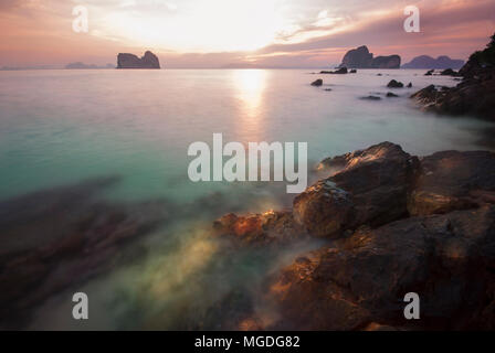 Montée du soleil sur le rock beach sur l'île de la mer dans le sud de Ngai de Thaïlande. Arrière-plan la Montagne contre le ciel rouge et bleu turquoise emeraude wat Banque D'Images