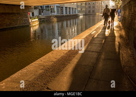 Un couple marcher leur chien le long du chemin de halage du Regents Canal au coucher du soleil un soir d'été Banque D'Images