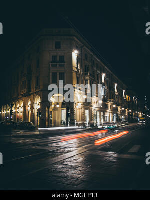 L'une des rues principales dans le centre de Turin avec les arcades illuminées la nuit de tir alors que les phares des voitures rouge sifflant Banque D'Images