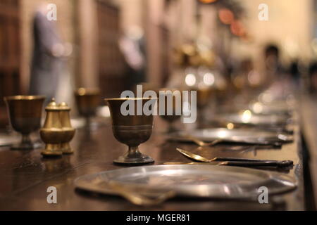 Une antique verre placé sur une table en bois avec des plaques de laiton antique et plaques, l'accent de verre tandis que le reste de l'image apparaît floue Banque D'Images
