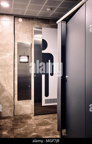 Un coup d'intérieur d'une salle de toilette pour hommes. Un grand homme signe sur la porte des toilettes à côté du sèche-serviettes. Banque D'Images