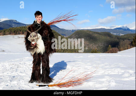 Un garçon pose dans son costume Krampus, tenant son masque dans ses mains, près de la ville de Castelrotto (Kastelruth), le Tyrol du Sud, Italie Banque D'Images