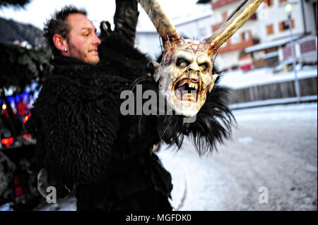 Un homme est sur le point de porter un masque de Krampus avant de prendre part au défilé traditionnel dans la ville de Castelrotto (Kastelruth), Italie Banque D'Images