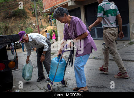 27 avril 2018, le Venezuela, Caracas : Une vieille femme portant une cruche d'eau sur un vieux panier à travers le Las Minas trimestre qu'elle en a l'air d'une source d'eau. L'approvisionnement en eau potable a été interrompu il y a 20 jours dans ce trimestre. De nombreuses personnes protestent dans plusieurs villes du pays. Les protestations ont été convoqués en raison de problèmes avec l'approvisionnement à travers les entreprises publiques. Photo : Manu Quintero/dpa Banque D'Images