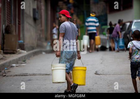 27 avril 2018, le Venezuela, Caracas : un homme portant deux seaux par Las Minas le trimestre en raison de la rareté de l'eau potable. L'approvisionnement en eau potable a été interrompu il y a 20 jours dans ce trimestre. De nombreuses personnes protestent dans plusieurs villes du pays. Les protestations ont été convoqués en raison de problèmes avec l'approvisionnement à travers les entreprises publiques. Photo : Manu Quintero/dpa Banque D'Images