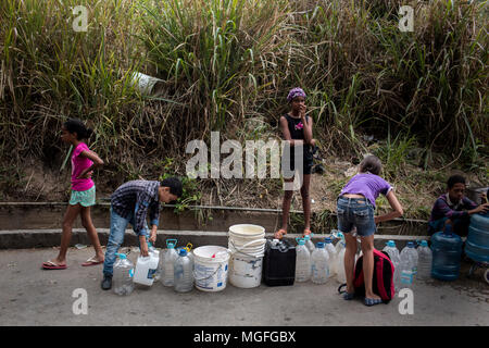 27 avril 2018, le Venezuela, Caracas : Les enfants se tenant dans la ligne et en attente de leurs bidons et seaux à remplir avec l'eau potable. L'approvisionnement en eau potable a été interrompu il y a 20 jours dans ce trimestre. De nombreuses personnes protestent dans plusieurs villes du pays. Les protestations ont été convoqués en raison de problèmes avec l'approvisionnement à travers les entreprises publiques. Photo : Manu Quintero/dpa Banque D'Images