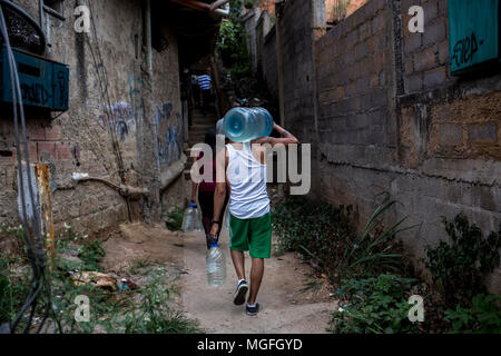 27 avril 2018, le Venezuela, Caracas : un homme portant une cruche avec de l'eau par le Las Minas trimestre en raison de la rareté de l'eau potable. L'approvisionnement en eau potable a été interrompu il y a 20 jours dans ce trimestre. De nombreuses personnes protestent dans plusieurs villes du pays. Les protestations ont été convoqués en raison de problèmes avec l'approvisionnement à travers les entreprises publiques. Photo : Manu Quintero/dpa Banque D'Images