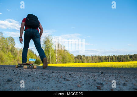 Un homme monte un longboard en arrière-plan du paysage rural, de déplacement pour longborne, le gars dans la chemise rouge sur une planche à roulettes Banque D'Images