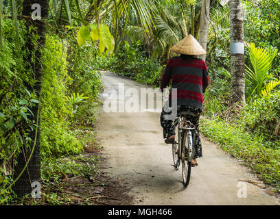 Vietnamese woman riding sa bicyclette sur le chemin dans la région du delta du Mékong du Vietnam Banque D'Images