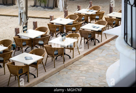 Porto Pollensa, Mallorca, Espagne. En 2018. Tables et chaises de plage set pour le petit déjeuner tôt le matin dans la lumière. Banque D'Images