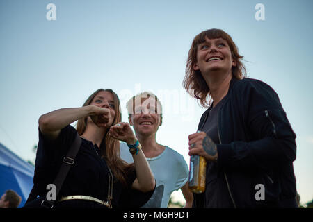 Göteborg / Suède - 13 août 2015 : Trois personnes debout, contre un bleu clair ciel du soir, sourire, parler et s'amuser ensemble Banque D'Images