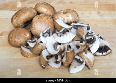 Champignons Portobello bébé entières ou coupées en tranches sur une planche à découper en bois macro closeup Banque D'Images