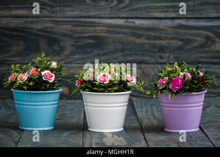 Fleurs artificielles en pots décoratifs bleu sur fond de bois Banque D'Images