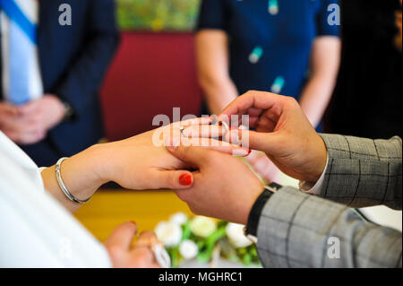 Groom portant un anneau au doigt de la mariée lors de la cérémonie du mariage Banque D'Images