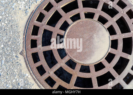 Metal fonte couvercle de trou d'pluie en piste avec des vitraux de boue l'eau de pluie entourant l'entrée des barbecues de ce lourd couvercle d'entrée Banque D'Images