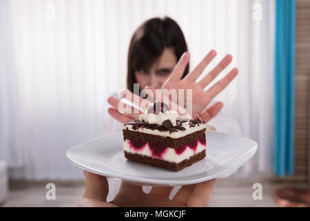 Femme refusant tranche de gâteau délicieux offerts par une personne Banque D'Images