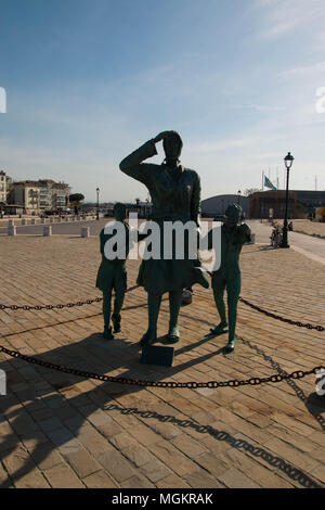 Dei marinai' 'Sposent, une statue en bronze de l'artiste Pagliarani célébrant les épouses des marins, situé à Cesenatico, Italie. Vue avant rétroéclairé. Banque D'Images